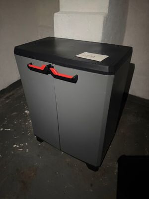 a grey cabinet with a red handle in a room