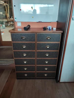 une commode avec des tiroirs et un tableau blanc posé dessus