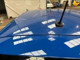 a blue car parked in a parking lot with windows on the roof