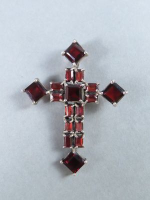 un gros plan d'une croix composée de grenats sur un fond blanc