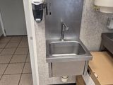 a sink in a public restroom with boxes on the floor