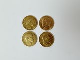 quatre types différents de pièces d'or reposant sur une surface blanche