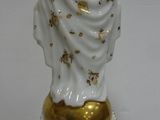 a white and gold statue of a woman on a stand