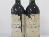 two bottles of red wine sitting on top of a white table
