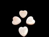 three white heart shaped shells on a black background