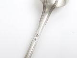 a silver spoon with a handle on a white surface