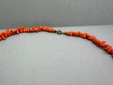une photo d'un collier composé de perles de corail orange et muni d'un fermoir en or