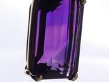 someone holding a purple stone in their hand with a sky in the background