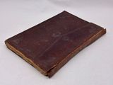 an old brown book sitting on top of a white table
