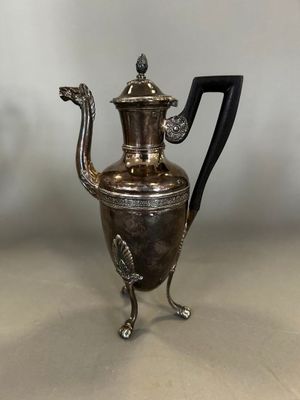 cafetière plaquée argent avec une poignée noire, posée sur un socle