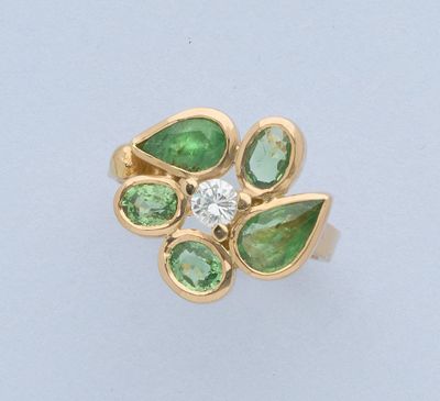 gros plan d'une bague en or avec des pierres vertes et blanches