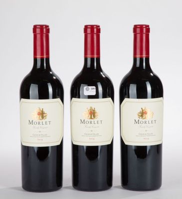 trois bouteilles de vin rouge posées l'une à côté de l'autre sur une surface blanche