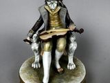 figurine of a man sitting on a chair holding a book and a dog