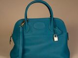 blue leather handbag with a padlock on top of it