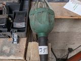 une perceuse verte posée sur une palette en bois, à côté d'une boîte à outils