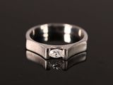 a close up of a ring with a diamond on a black surface