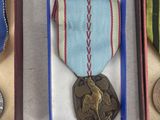 three medals are in a wooden box on a white surface