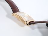 a gold watch with a brown strap on a white surface
