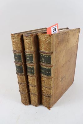trois vieux livres sont empilés sur une surface blanche