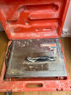 une boîte à outils rouge contenant un outil, posée sur un plancher en bois