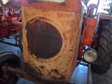 a rusted tractor in a garage with other tractors in the background