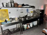 a kitchen with a sink, stove, and a counter with pots and pans on it