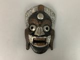 un masque en bois accroché à un mur blanc