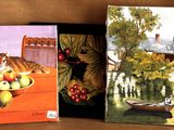 three paintings on a shelf with a cat and a bowl of fruit