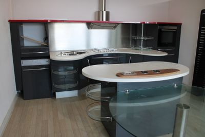 une cuisine avec un plan de travail en verre et des placards noirs