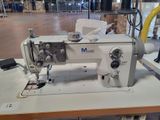 a white sewing machine on a table in a warehouse