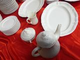 many plates and cups on a table with a red cloth