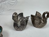 two silver figurines of swans sitting on a table
