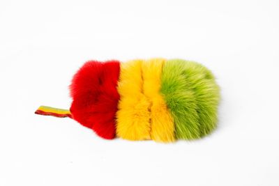 un gros plan sur un pompon rouge, jaune et vert posé sur une surface blanche