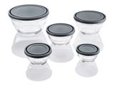 quatre bols en verre avec des couvercles noirs, posés sur une surface blanche