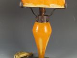 une lampe orange avec un pied vert et un abat-jour jaune