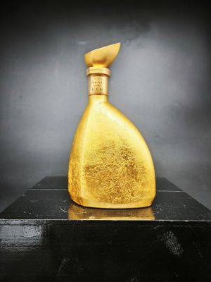 une image représentant une bouteille dorée posée sur une table noire