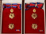 two boxes with medals and ribbons on them on a table