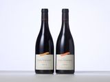 two bottles of red wine sitting on top of a table