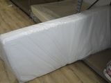 Des cartons contenant des matelas sont empilés les uns sur les autres dans une pièce