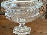 a glass bowl on a wooden table with a floral wallpaper behind it