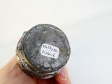 une personne tenant une bouteille sur laquelle est collé un autocollant