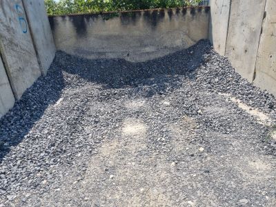 a pile of gravel in the corner of a concrete wall