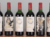 six bottles of wine are lined up on a wooden table