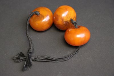 trois tomates suspendues à une ficelle posée sur une table