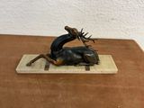 a bronze statue of a deer and a man on a board