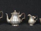 four pieces of silver tea and coffee set on a black background