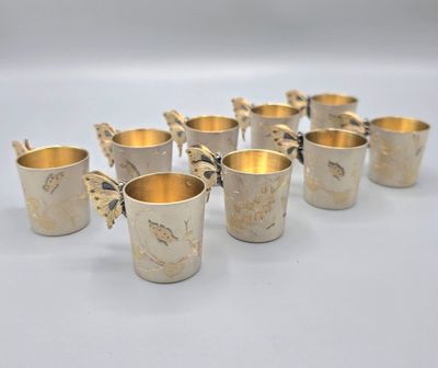 six silver cups with butterflies on them are lined up in a row