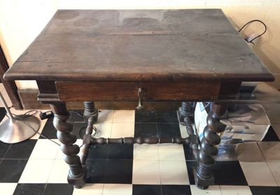 une table avec un plateau en bois posée sur un sol à damier noir et blanc