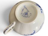 a small cup and saucer with a handle on a white surface