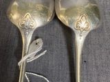 pair of silver spoons on a gray surface with a tag